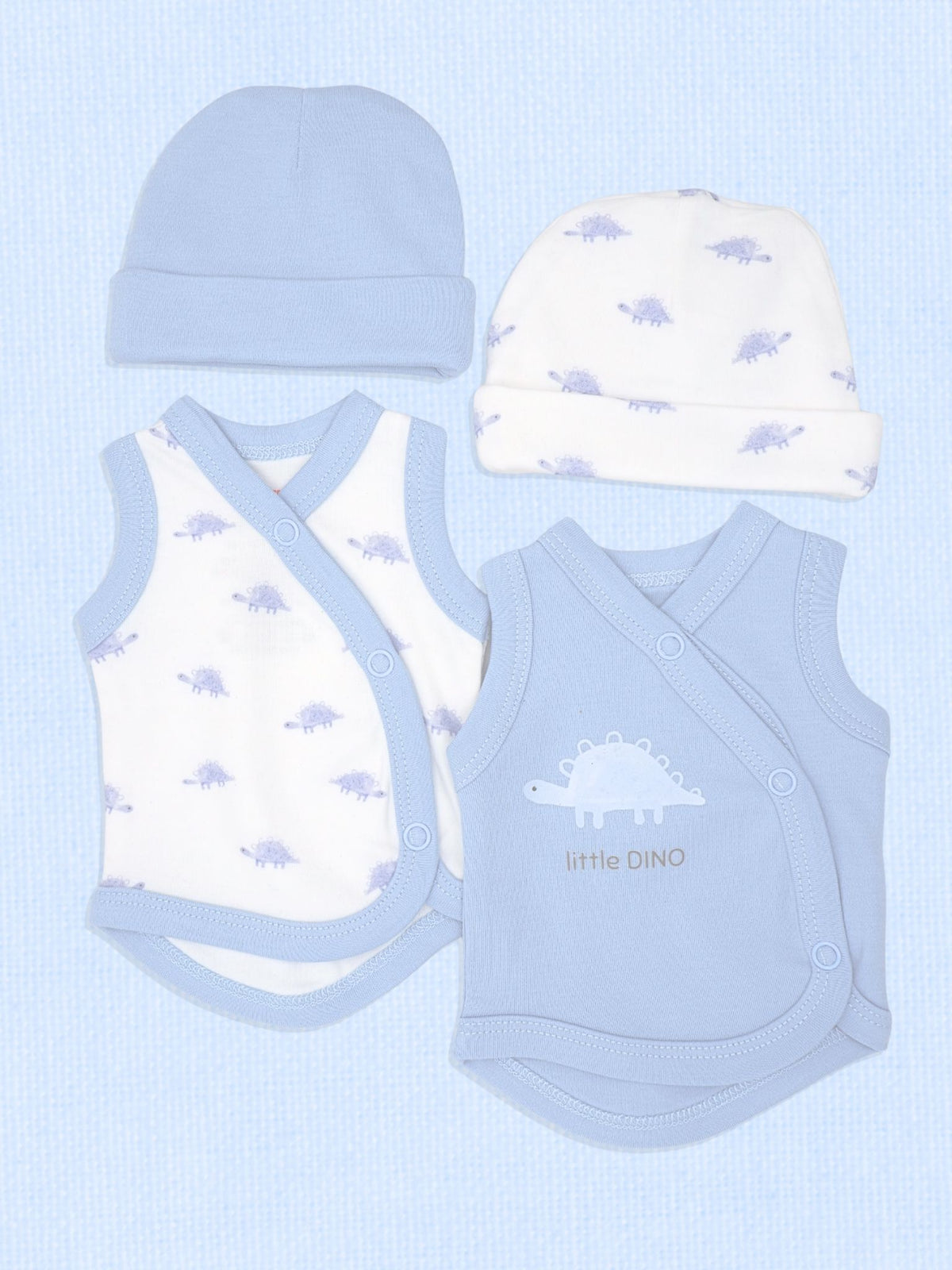 A baby clothing set laid flat on a light blue textured background, including a light blue beanie, a white beanie with small purple dinosaur prints, a white wrap bodysuit with light blue trim and dinosaur prints, and a light blue wrap bodysuit with a white dinosaur graphic and the words 'little DINO'.