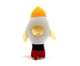 A knitted plush toy shaped like a rocket ship, shown from the back on a clean white background. The rocket features a white body, a yellow-orange pointed nose, a yellow circular window, light yellow wings, a black band, and red feet. Perfect to combine with one of ur premature baby clothes. We also provide gift shipping