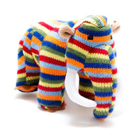 A knitted stuffed elephant toy with horizontal rainbow stripes in red, orange, yellow, green, blue, and white, featuring brown ears and trunk base, photographed on a white background.
