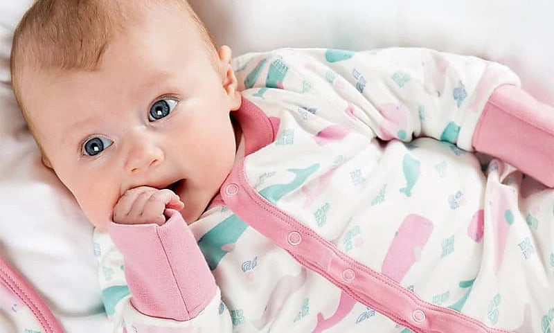 Baby in a colorful outfit with pink accents on a white background