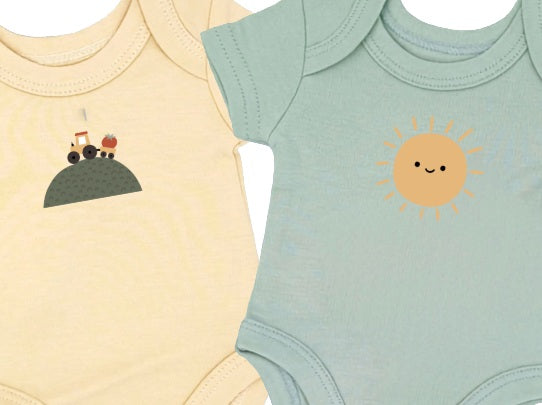 Two baby bodysuits, one yellow with a tractor design and one green with a sun design, on a white background.