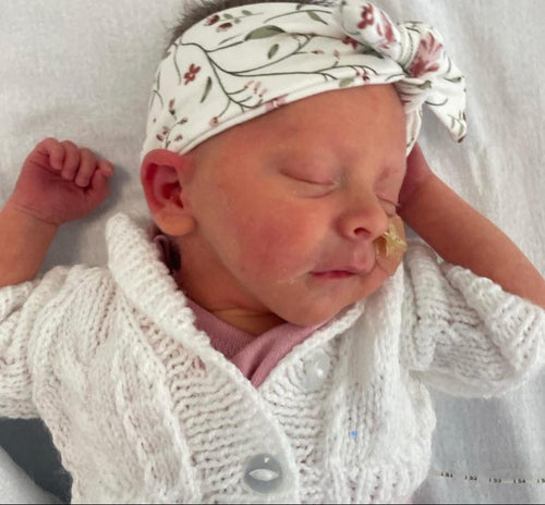 Premature baby girl in headband and cardigan