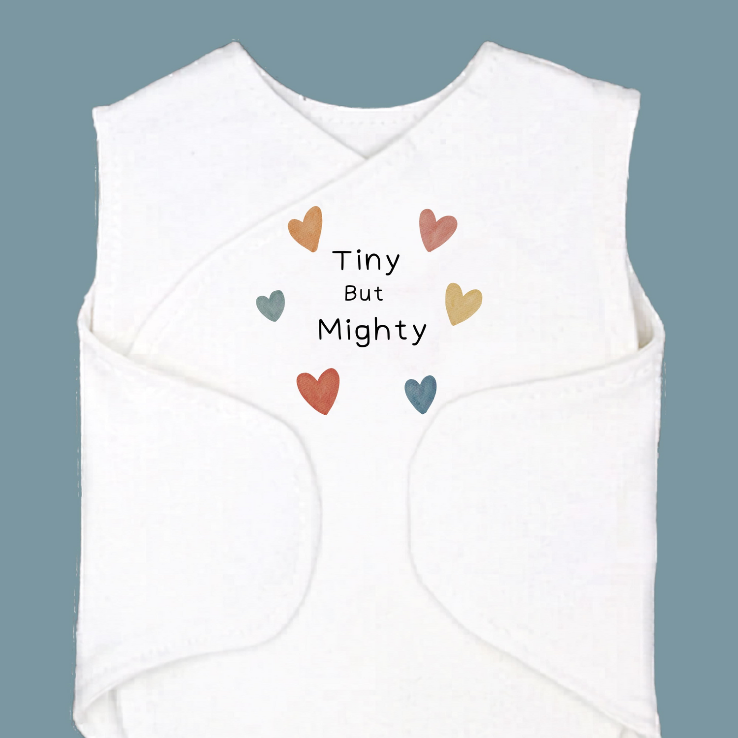 White baby romper with colorful hearts and 'Tiny But Mighty' text on a blue background